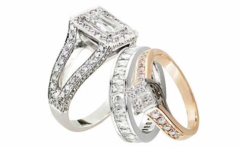 Three precious metal rings with large and small diamonds.